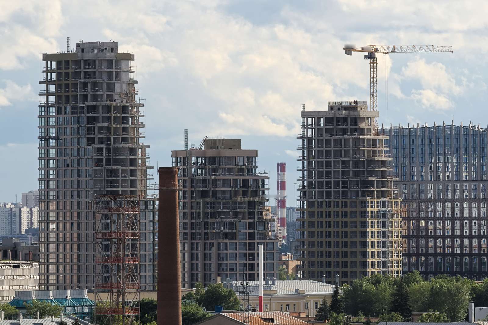 Tres torres residenciales de hormigón en construcción al mismo tiempo, con andamios, grúa torre y fachadas en etapas distintas